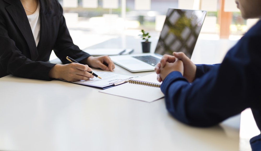 A naturopathic doctor signing a requisition across a bright desk with a patient — ordering under their own license.